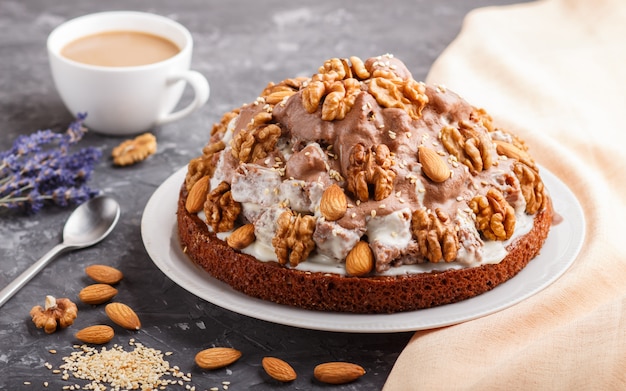 Gâteau fait maison avec de la crème de lait, du cacao, des amandes, des noisettes avec du textile orange et une tasse de café. Vue de côté.