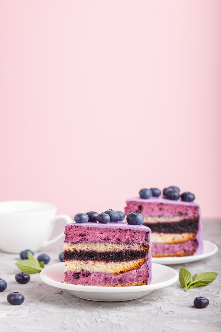 Photo gâteau fait maison avec de la crème de souffle et de la confiture de bleuets avec une tasse de café sur fond gris et rose. vue de côté.