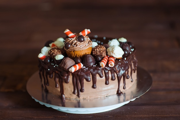 Gâteau fait maison décoré de bonbons, cupcakes et gaufres.