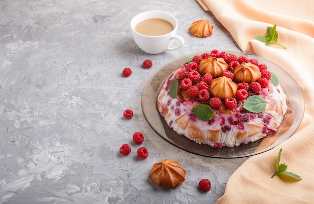 Gâteau fait maison avec du lait, des biscuits et des framboises avec une tasse de café et de textile orange, vue de côté.