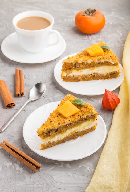 Gâteau fait maison avec kaki et citrouille et une tasse de café sur une surface de béton gris avec textile jaune