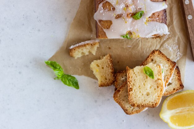 Gâteau fait maison de pain au citron décoré avec du zeste de citron, du basilic et des copeaux de noix de coco.