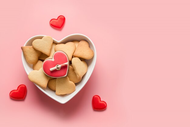 Gâteau fait maison pour la Saint Valentin. Biscuits en forme de coeur en plaque sur rose. Vue d'en-haut.