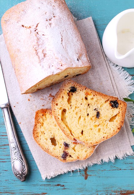 Gâteau fait maison avec des raisins secs et des noix coupées en morceaux sur un fond bleu