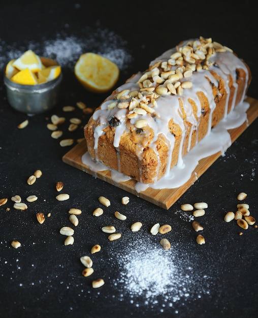 Gâteau fait maison avec des raisins secs et des noix avec du glaçage au citron sur fond sombre, Pâtisserie, Photo atmosphérique, Gâteau au citron, Mise au point sélective, Vertical