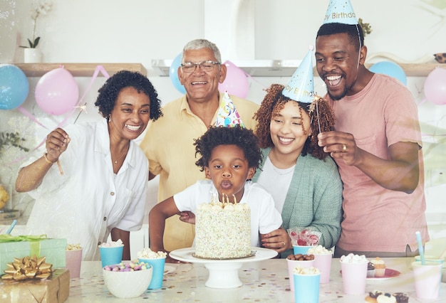 Gâteau de fête d'anniversaire et soufflez avec la famille dans la cuisine pour célébrer le lien et le bonheur affectueux excité et les grands-parents avec les parents et l'enfant à la maison pour un plaisir et un événement surprise