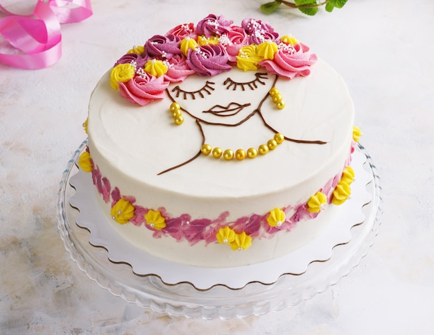 Photo gâteau de fête avec des fleurs crème et un visage de fille sur fond clair