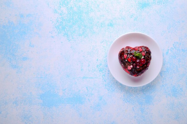 Gâteau en forme de coeur avec canneberges, menthe et chocolat sur fond bleu avec place pour le texte. La Saint-Valentin