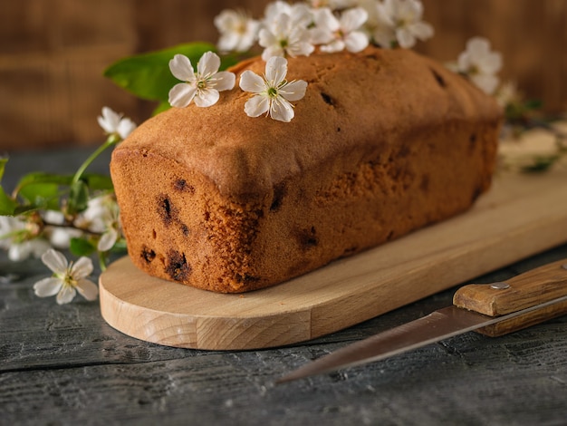 Gâteau fraîchement sorti du four avec des raisins secs en fleurs de cerisier sur une table en bois. Délicieux gâteaux faits maison.