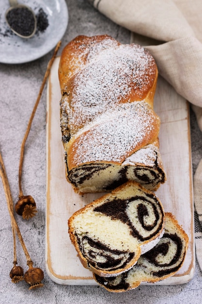 Gâteau avec garniture de pavot et têtes de graines sur fond de béton gris. Style rustique, mise au point sélective.