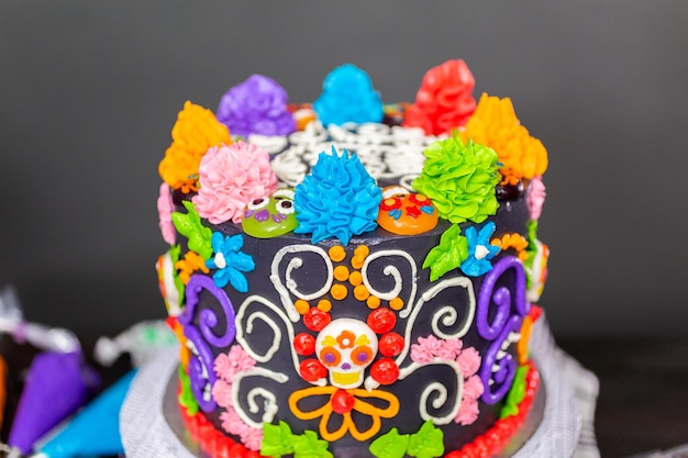 Gâteau gastronomique Dia de los Muertos décoré d'un glaçage coloré à la crème au beurre et de cupcakes gommeux.