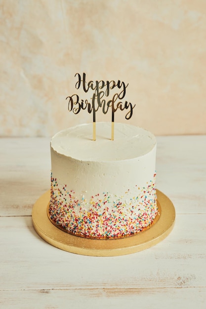 Gâteau avec un gâteau ''joyeux anniversaire'' et saupoudre sur une planche de bois sur la table