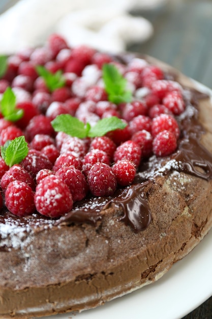 Gâteau avec glaçage au chocolat et framboises sur fond de bois