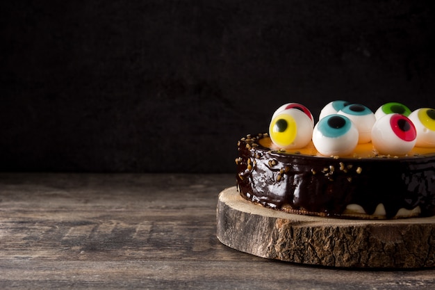 Gâteau d'Halloween à la décoration des yeux de bonbon sur une table en bois. Espace de copie