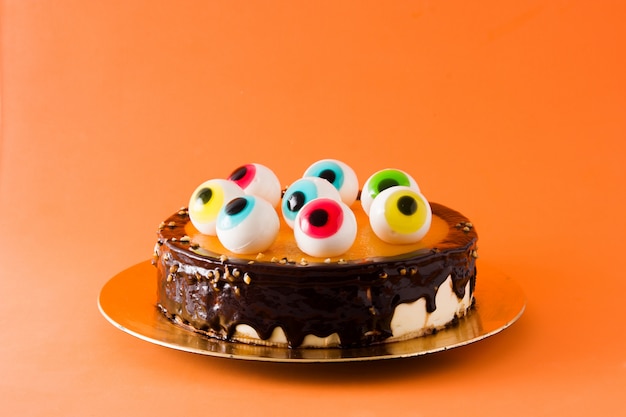 Gâteau d'Halloween avec décoration yeux bonbons sur fond orange