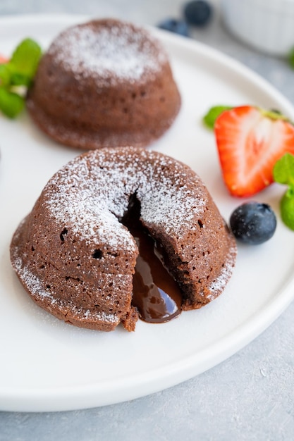 Gâteau de lave fondant au chocolat avec des baies fraîches sur une assiette sur fond gris