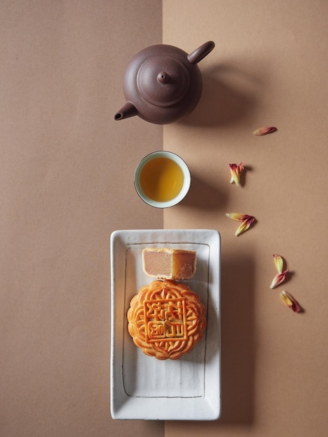 Gâteau de lune sur une assiette et un quart de coupe montrant le thé farci servi dans une tasse et une théière Gâteau chinois traditionnel pour le Festival de la mi-automne Vue de dessus