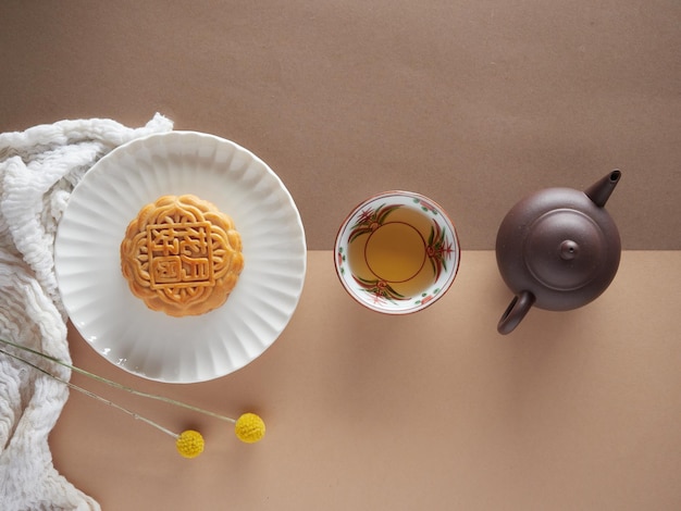 Gâteau de lune sur une assiette tasse de thé petite théière et fleurs jaunes Composition minimaliste vue d'en haut avec espace de copie concept de festival de la mi-automne