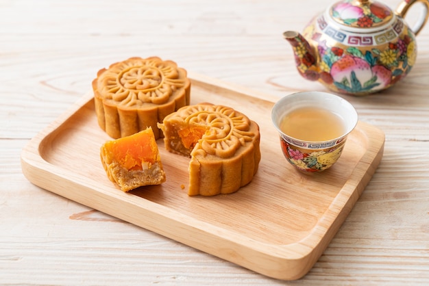 Gâteau de lune chinois au durian et saveur de jaune d'oeuf avec du thé sur une plaque de bois