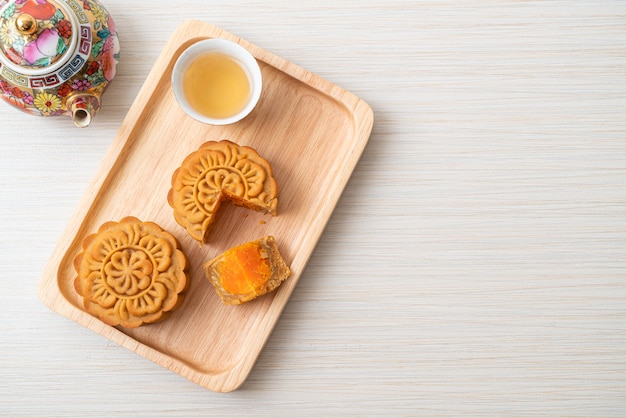 Gâteau de lune chinois durian et saveur de jaune d'oeuf avec du thé sur plaque de bois