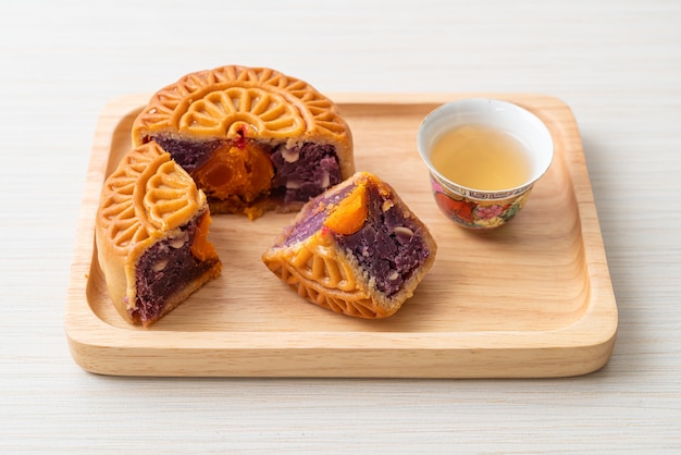 Gâteau de lune chinois saveur de patate douce violette avec du thé sur une plaque de bois