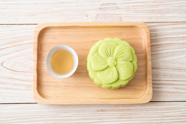 Gâteau de lune chinois saveur de thé vert avec thé sur plaque de bois