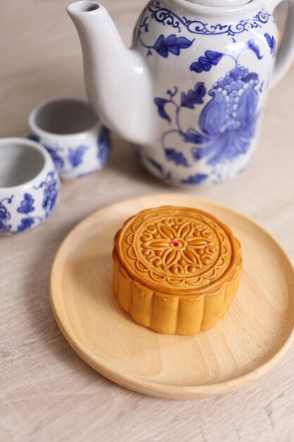 Un gâteau de lune sur un plat en bois et une théière chinoise sur un fond en bois