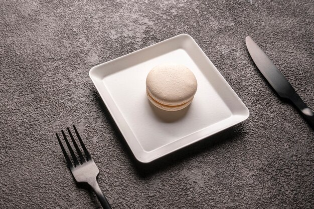 gâteau de macaron blanc dans une assiette blanche élégante. fermer. dessert pour le café, service de table, fourchette et couteau noirs