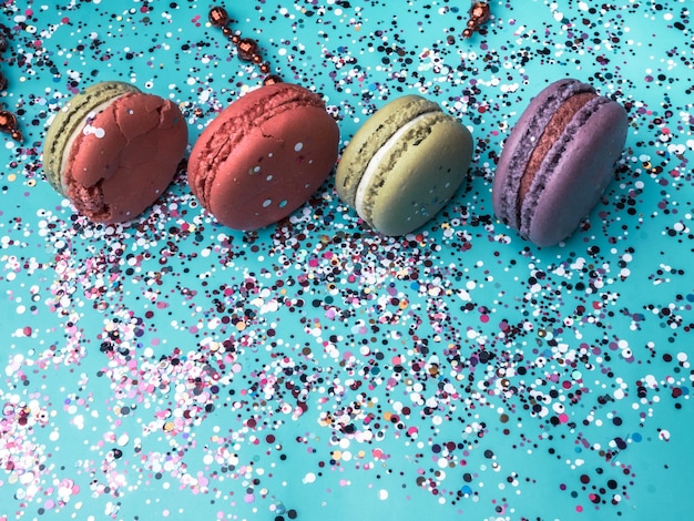 Gâteau macaron ou macaron sur fond turquoise avec confettis colorés biscuits aux amandes carte festive mise au point sélective