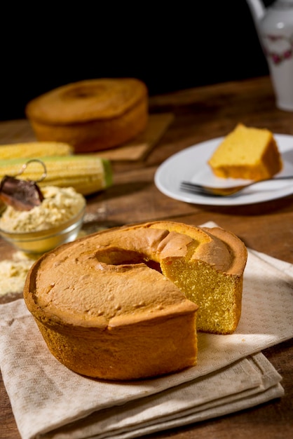 Gâteau de maïs sans tranche sur bois rustique et tissu avec du maïs, tranche dans l'assiette et gâteau en arrière-plan.