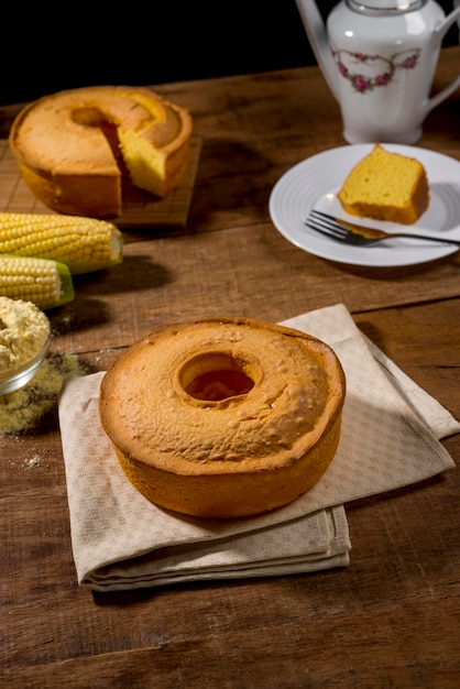 gâteau de maïs sur une table en bois rustique avec une tranche de maïs dans une assiette et un gâteau en arrière-plan