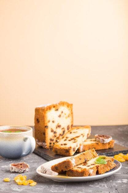 Gâteau maison aux raisins secs, kaki séché et une tasse de chocolat chaud sur un fond noir et orange.