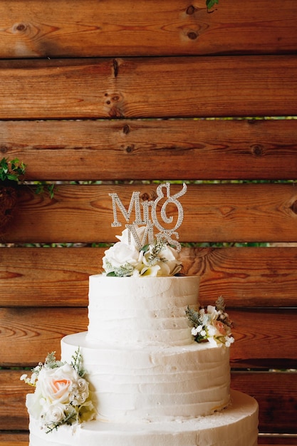 Gâteau de mariage blanc contre un fond de mur en bois