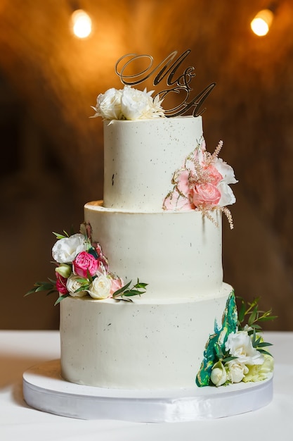 Gâteau de mariage blanc élégant décoré de fleurs fraîches et d'or.