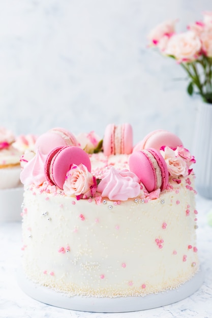 Gâteau de mariage blanc avec macarons et roses