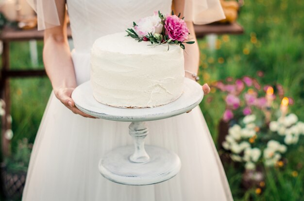 Gâteau de mariage dans les mains de la mariée