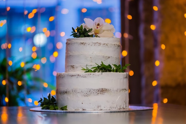 Gâteau de mariage à deux niveaux avec des fleurs naturelles sur fond flou