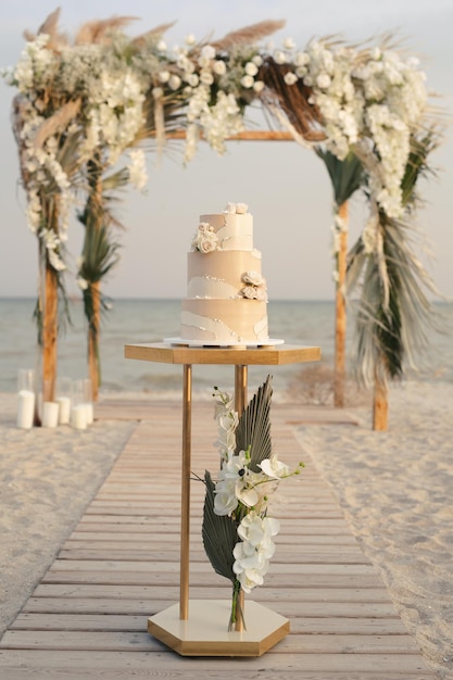 Gâteau de mariage lors d'un mariage à la plage sur le fond d'une belle arche pour une cérémonie de sortie