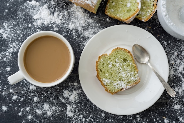 Gâteau à la menthe saupoudré de sucre en poudre sur une surface sombre avec une tasse de café