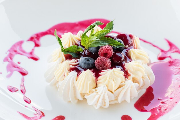 Gâteau de meringue aux fruits rouges sur une plaque blanche