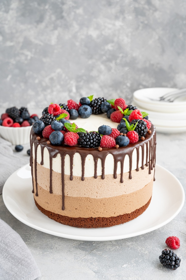 Photo gâteau mousse aux trois chocolats avec glaçage au chocolat myrtilles framboises et mûres
