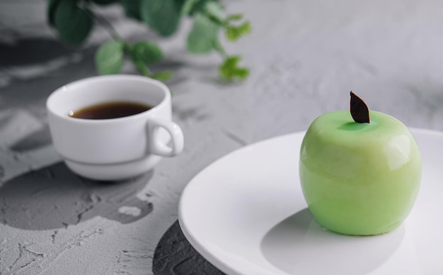 Un gâteau mousse en forme de pomme verte et une tasse de café