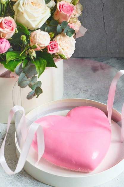 gâteau mousse rose en forme de coeur et un grand bouquet de belles fleurs