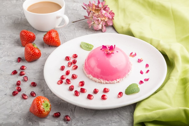 Gâteau mousse rose à la fraise et une tasse de café sur une surface de béton gris et textile vert