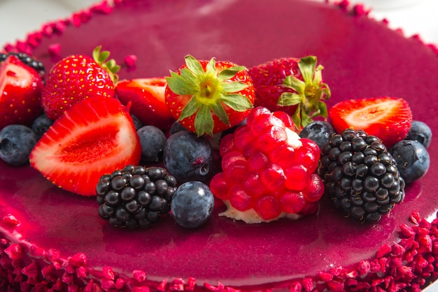 Gâteau mousse rouge avec décor de baies sur la table se bouchent