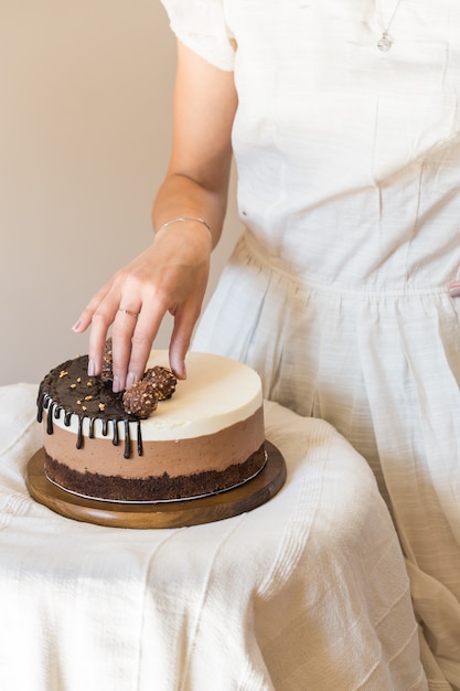 Gâteau mousse "trois chocolat". Morceau de gâteau composé de trois couches de chocolat de différentes couleurs souffle dans la main de la femme