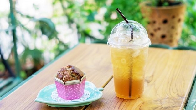 Gâteau muffin et thé glacé sur une table en bois.