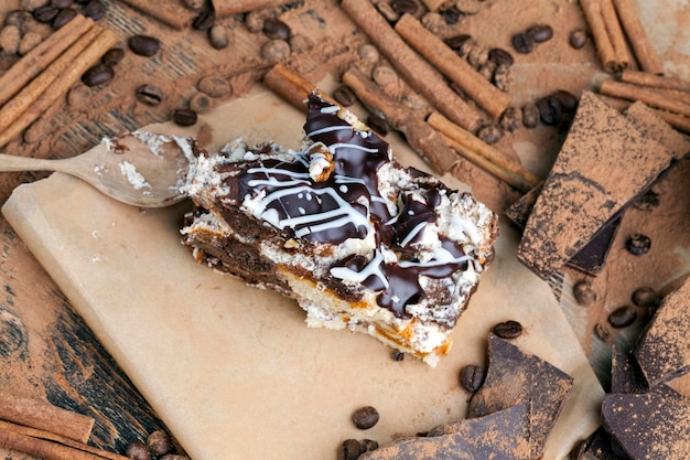 Un gâteau multicouche composé de gâteaux au chocolat et à la crème dans un ordre chaotique dans le lot de gâteaux de cannelle au chocolat et de poudre de cacao éparpillés autour du gâteau