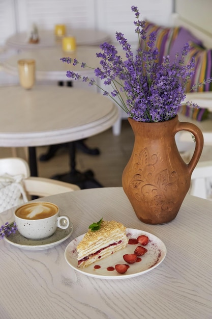 Gâteau napoléon naturel et tasse de cappuccino sur une table en bois dans le café Lavande dans la cruche Temps de café esthétique Temps pour soi