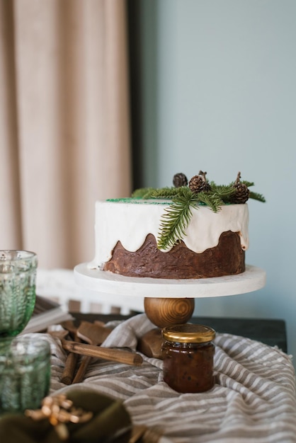 Un gâteau de Noël festif avec du glaçage blanc décoré de branches d'épice se tient sur une table.